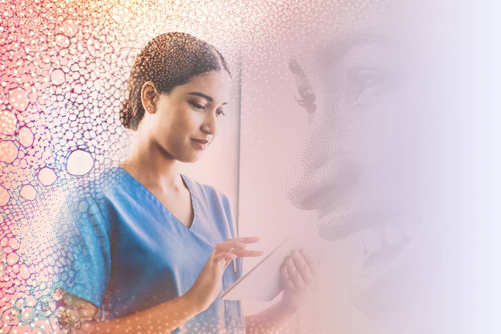 A woman in a clinical setting holding an iPad and appearing to read something on it